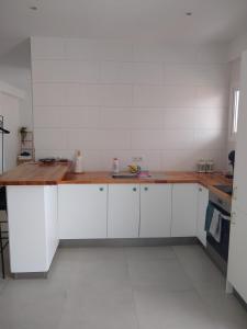 a kitchen with white cabinets and a wooden counter top at Maestro Concepcion Guidet in Fuengirola