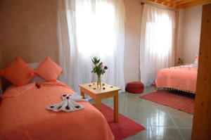 - une chambre avec 2 lits et un vase de fleurs sur une table dans l'établissement Riad Essaouira, à Essaouira