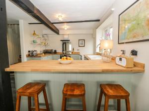 a kitchen with a counter with two stools at Waterside in Ravenglass