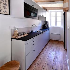 a kitchen with white cabinets and a black counter top at Le kocon, dans un écrin, le calme à la mer in Saint-Pair-sur-Mer