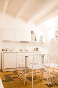 - une cuisine avec des placards blancs, une table et des chaises dans l'établissement Masseria Torrechiara Eco Dimora di Charme, à Castel del Monte