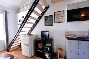 eine Küche mit einem Kühlschrank und eine Treppe in einem Zimmer in der Unterkunft Le kocon, dans un écrin, le calme à la mer in Saint-Pair-sur-Mer