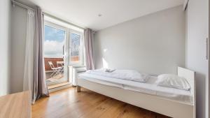 biała sypialnia z łóżkiem i dużym oknem w obiekcie Apartamenty Sun & Snow Plac Neptuna w mieście Międzyzdroje