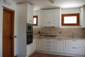 a white kitchen with white cabinets and a sink at B&B Profumo delle Marche in Montefano