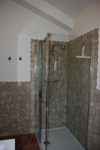 a shower in a bathroom with a stone wall at B&B Profumo delle Marche in Montefano +27 photos