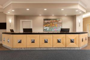 a lobby with a reception desk with a painting on the wall at Royal Hotel Calgary, Trademark Collection by Wyndham in Calgary