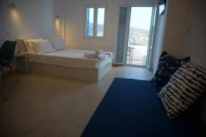 a bedroom with a bed and a couch and a window at Aiolos Studios Κythnos in Kithnos