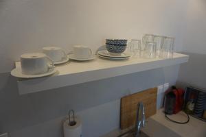 a shelf above a sink with cups and saucers at Aiolos Studios Κythnos in Kithnos