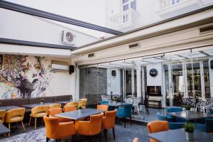 een restaurant met tafels en stoelen en een muur van ramen bij Bela Kuka Hotel in Bitola