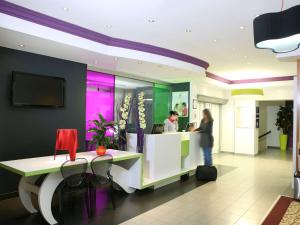 a woman standing at a counter in a lobby at ibis Styles Luzern in Lucerne
