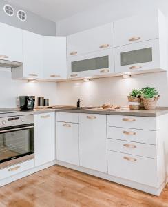 a white kitchen with white cabinets and two potted plants at Apartamenty Flat White Ruczajowa in Zielona Góra