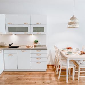 a kitchen with white cabinets and a dining table at Apartamenty Flat White Ruczajowa in Zielona Góra