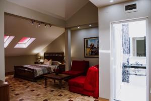 a bedroom with a bed and a red chair at Hotel Bela Kuka - White House in Bitola
