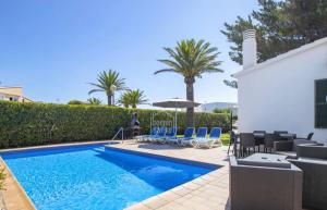 a swimming pool with chairs and a house at Villa Regina in Cala'n Bosch