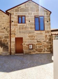 a stone house with a door and windows at Casas de Penedones - Ventos da Cabreira in Penedones