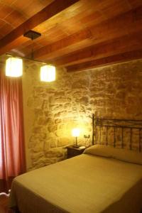 a bedroom with a bed and a stone wall at Casa Rural Ca Lazaro in Bot