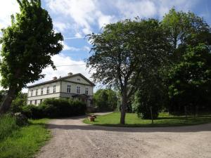 a white house with a tree and a dirt road at Amiralsgården Verstorp in Karlskrona