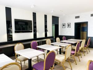 a dining room with white tables and purple chairs at Reikartz Sky Almaty in Almaty