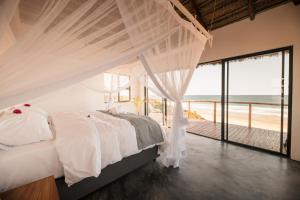 a bedroom with a bed with a view of the ocean at Kumba Lodge in Praia do Tofo