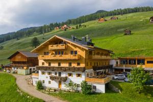 a large wooden building on a green hill with cars at Panorama in Sesto