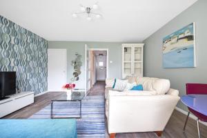 a living room with a white couch and a tv at Surbiton modern 2 bedroom flat with parking in Surbiton