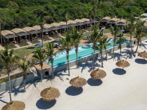 - une vue aérienne sur la piscine du complexe dotée de parasols en paille dans l'établissement San Martinho Hotel, à Vila Praia Do Bilene