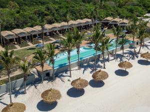 Vila Praia Do Bilene的住宿－San Martinho Hotel，享有带稻草遮阳伞的度假村游泳池的空中景致