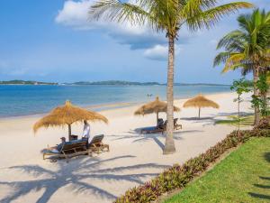 a group of people sitting on a beach with umbrellas at San Martinho Hotel in Vila Praia Do Bilene