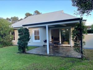 a small white house with a patio at Daisy Cottage in Hermanus
