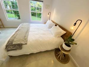 a bedroom with a large white bed with a potted plant at Daisy Cottage in Hermanus