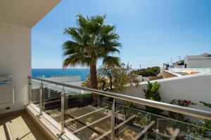 a balcony with a palm tree and the ocean at Cliff-Top Townhouse with Stunning Ocean Views in Carvoeiro