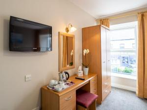 Habitación con escritorio y TV en la pared. en The Woodfield Hotel en Clifden