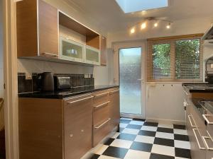 a kitchen with wooden cabinets and a checkered floor at Tivoli Bungalow in Weston-super-Mare