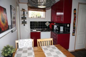 a small kitchen with red cabinets and a table with a tablecloth on it at Södra Emmetorpsgatan 31 in Borgholm
