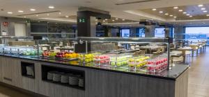 a kitchen with a buffet line with fruits and vegetables at Ilunion Calas de Conil in Conil de la Frontera