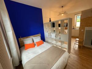 a bedroom with a blue wall and a bed with orange pillows at Studio design Bleu Alpin in Le Mont-Dore