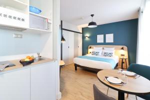 a bedroom with a bed and a table and a kitchen at Appart'City Confort Toulouse Diagora Labège in Labège