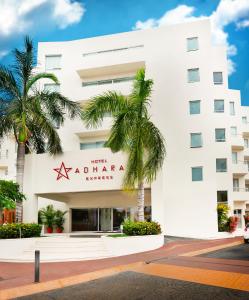 a white building with palm trees in front of it at Adhara Express in Cancún