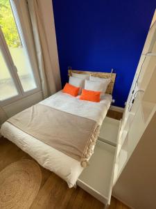 a small bed with two orange pillows in a room at Studio design Bleu Alpin in Le Mont-Dore