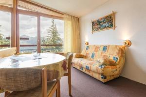 a living room with a table and a couch and a window at travelski home classic - Résidence les Lauzières in Arc 1800