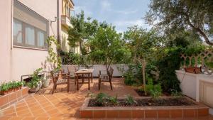 een patio met een tafel, stoelen en bomen bij Welcomely - Casa Lisa in Nuoro