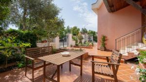 un patio con una mesa de madera y 2 bancos en Welcomely - Casa Lisa en Nuoro