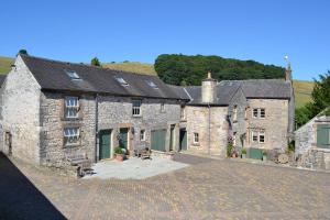 a large stone house with a driveway in front of it at Church Farm Holiday Cottages - Winnets Cottage in Ashbourne