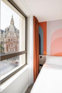 Schlafzimmer mit einem Fenster mit Blick auf ein Gebäude in der Unterkunft B&B HOTEL Antwerpen Centrum in Antwerpen