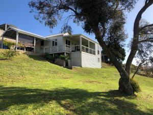 Ein weißes Haus auf einem Hügel mit einem Baum in der Unterkunft Twilight Cottage in Esperance