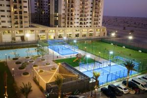 a tennis court in a parking lot next to a building at Beautiful apartment in amazing building having unique concept and experience in Dubai