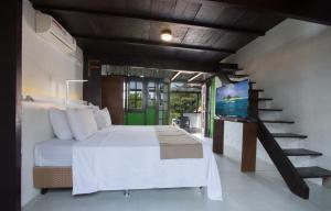 a bedroom with a bed and a staircase with a television at Pousada do Adriano in Búzios +34 photos