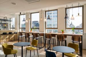 a bar with tables and chairs in a room with windows at B&B HOTEL Antwerpen Centrum in Antwerp
