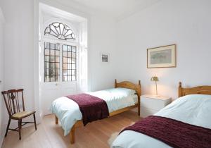 a bedroom with two beds and a chair and a window at Sandacres in North Berwick