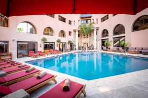 a large swimming pool with chairs and a building at Hivernage Hotel & Spa in Marrakesh